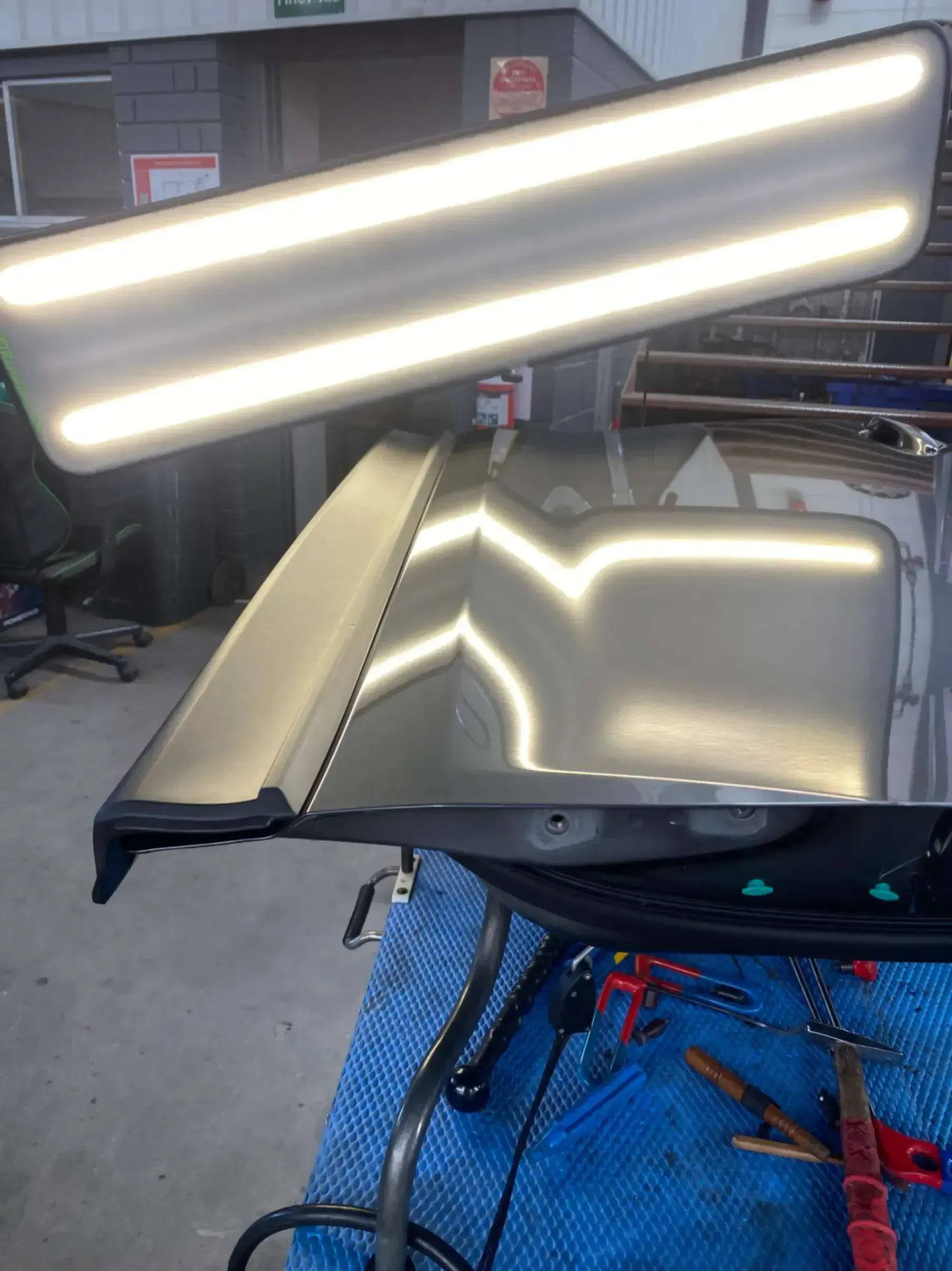 A piece of metal is sitting on a table with a light on it with dents removed.