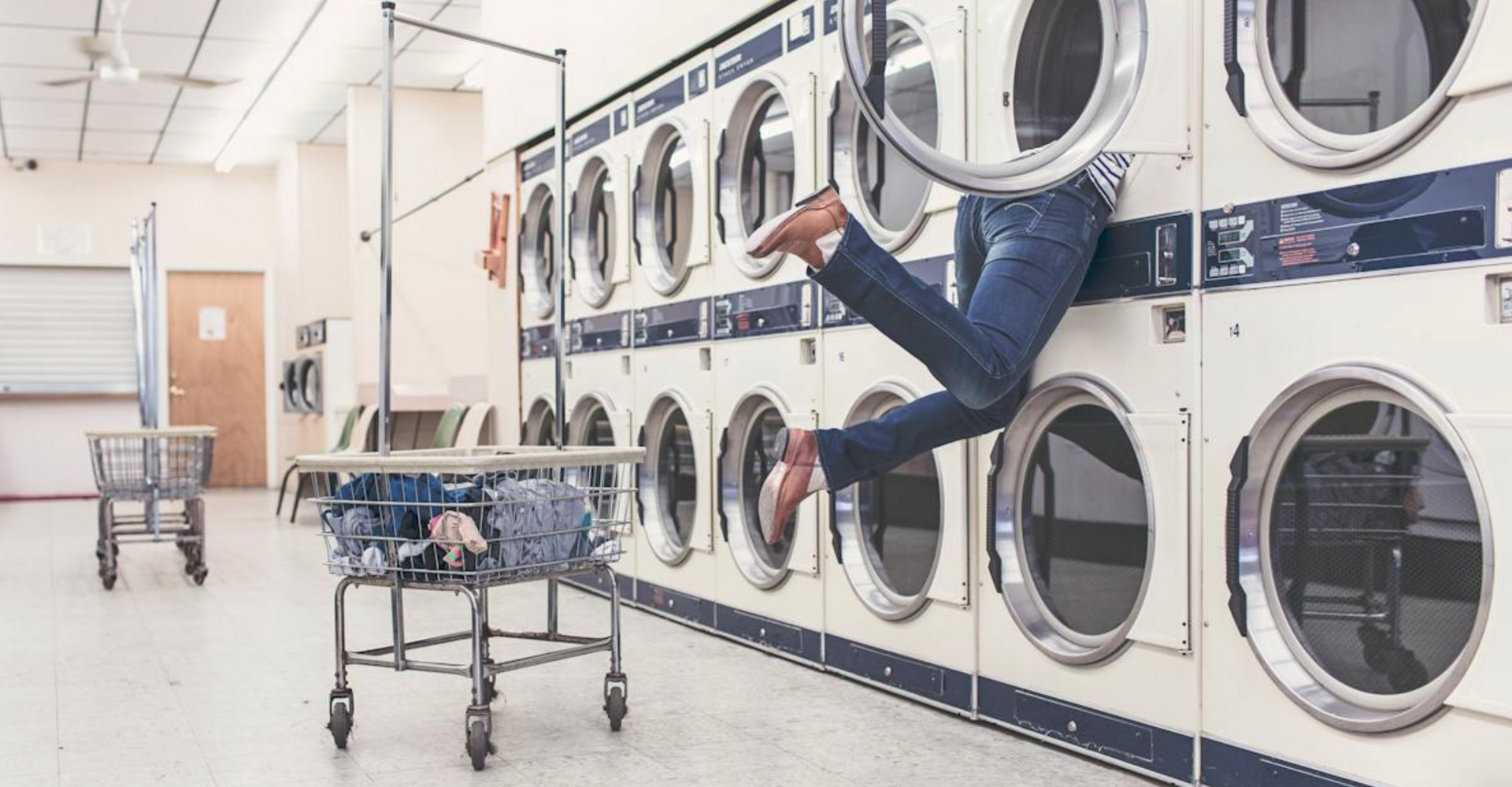 commercial laundry with rows of washing machines and dryers in a clean self service laundry facility