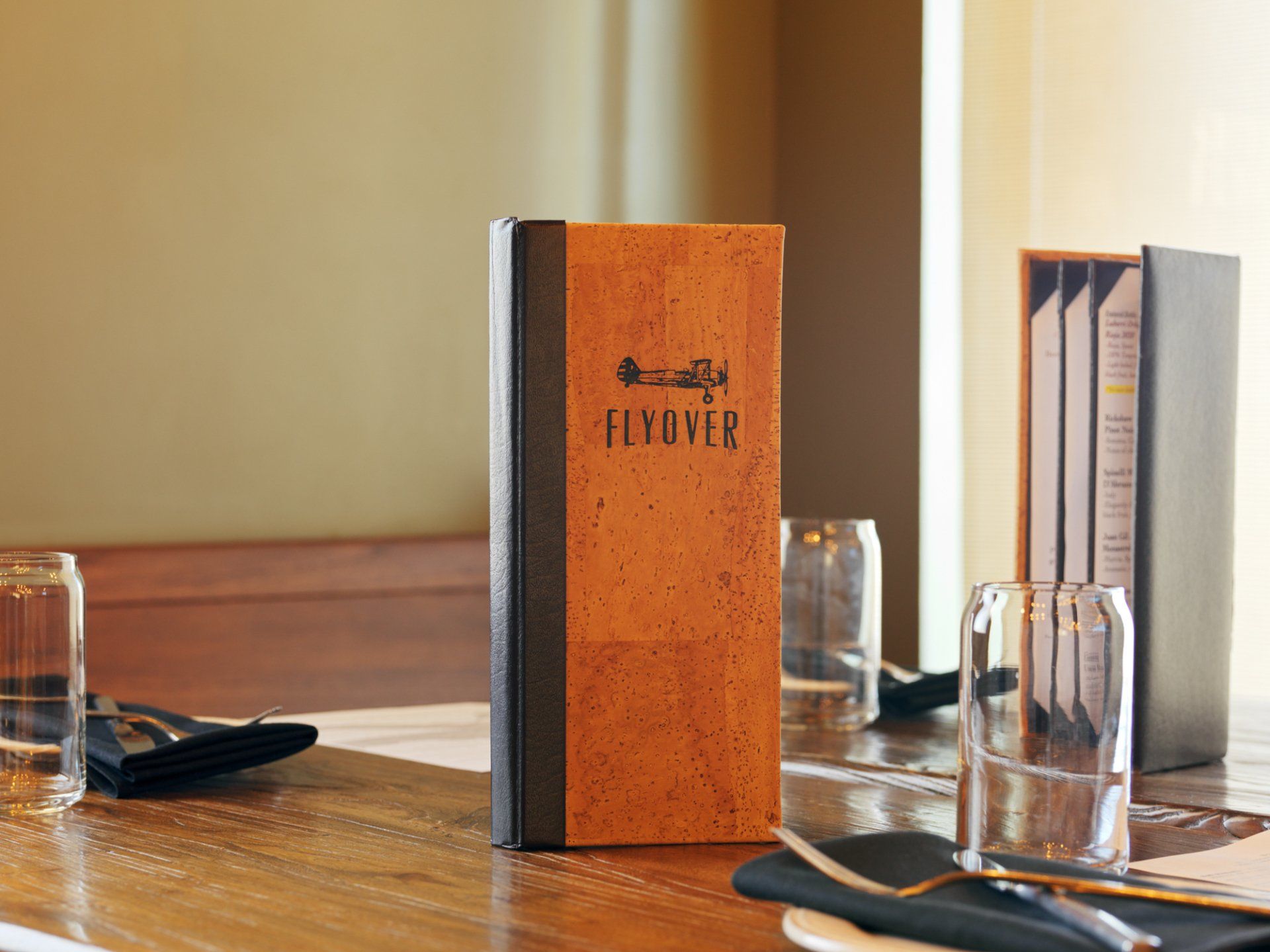 Orange FIVOVER menu standing on a restaurant table beside condiments and glassware