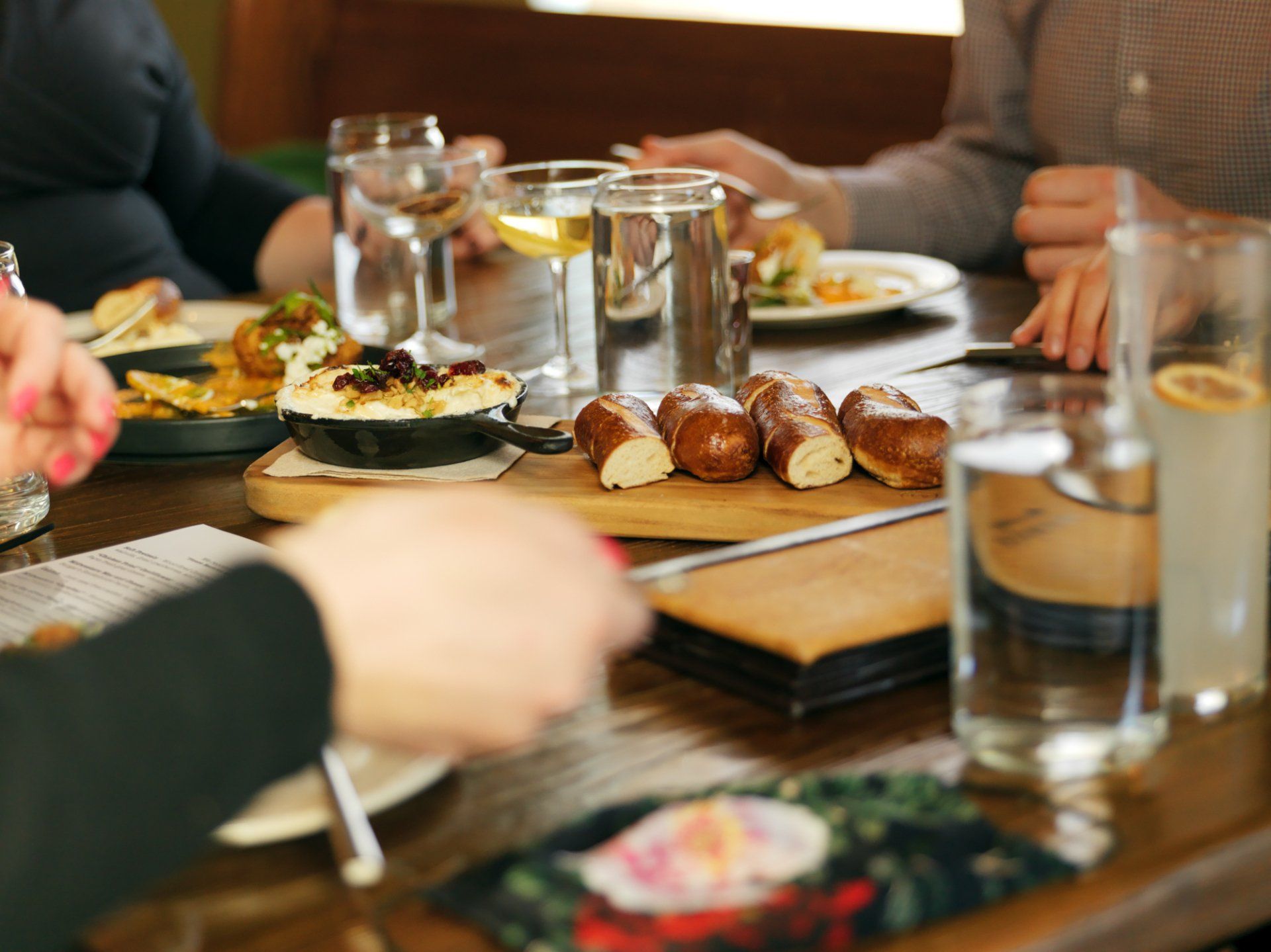 People sharing a meal at a table with glasses, bread, and plates in a warm restaurant setting