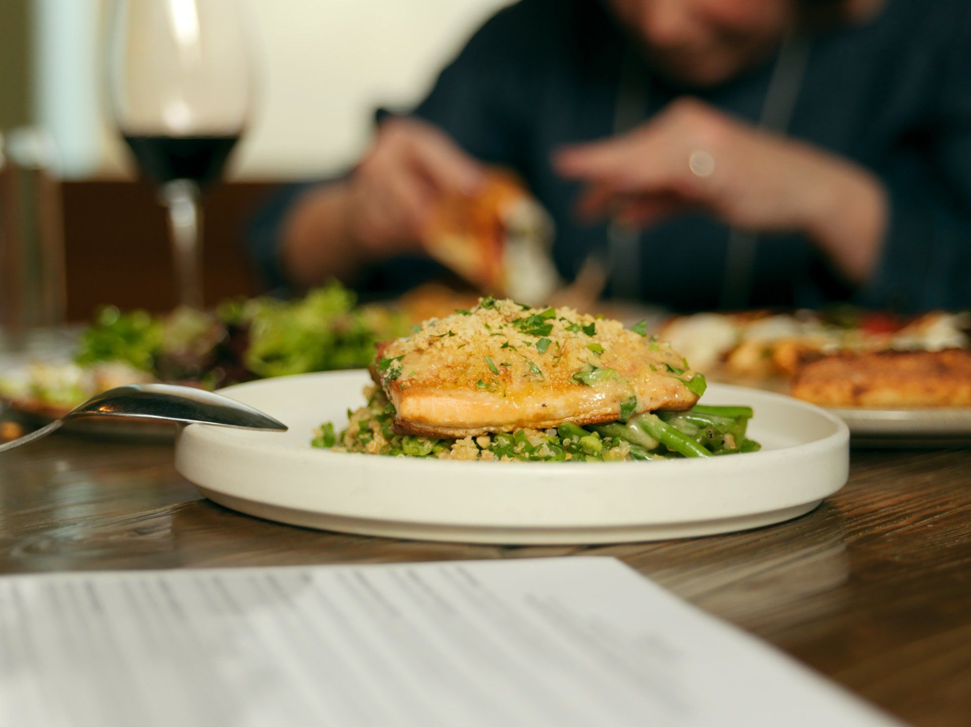 Plated salmon with asparagus on a restaurant table, with a blurred diner in the background