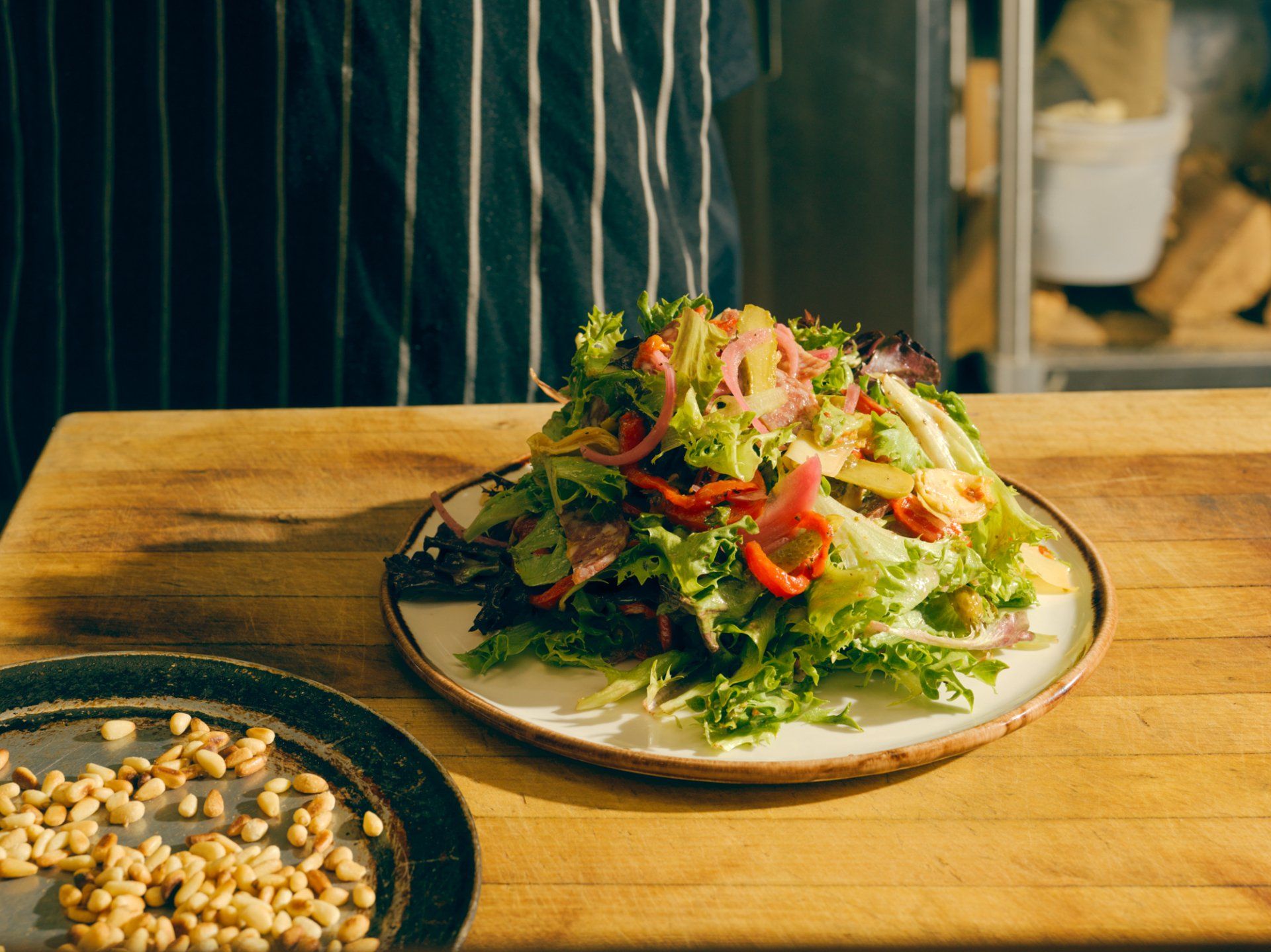 Salad with greens, vegetables, and sunflower seeds on a white plate on a wooden table