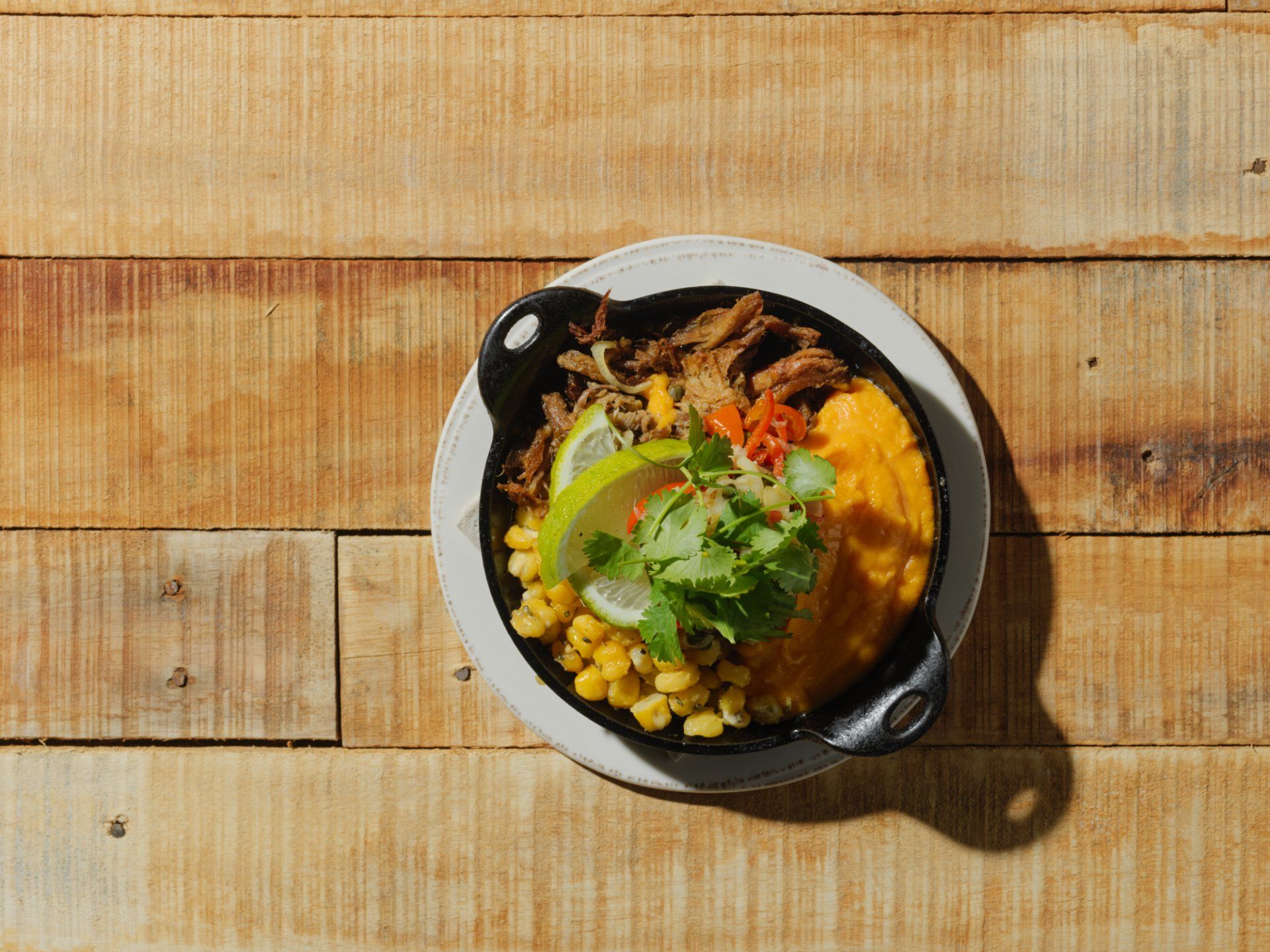 Bowl of colorful food with greens and chickpeas on a wooden table