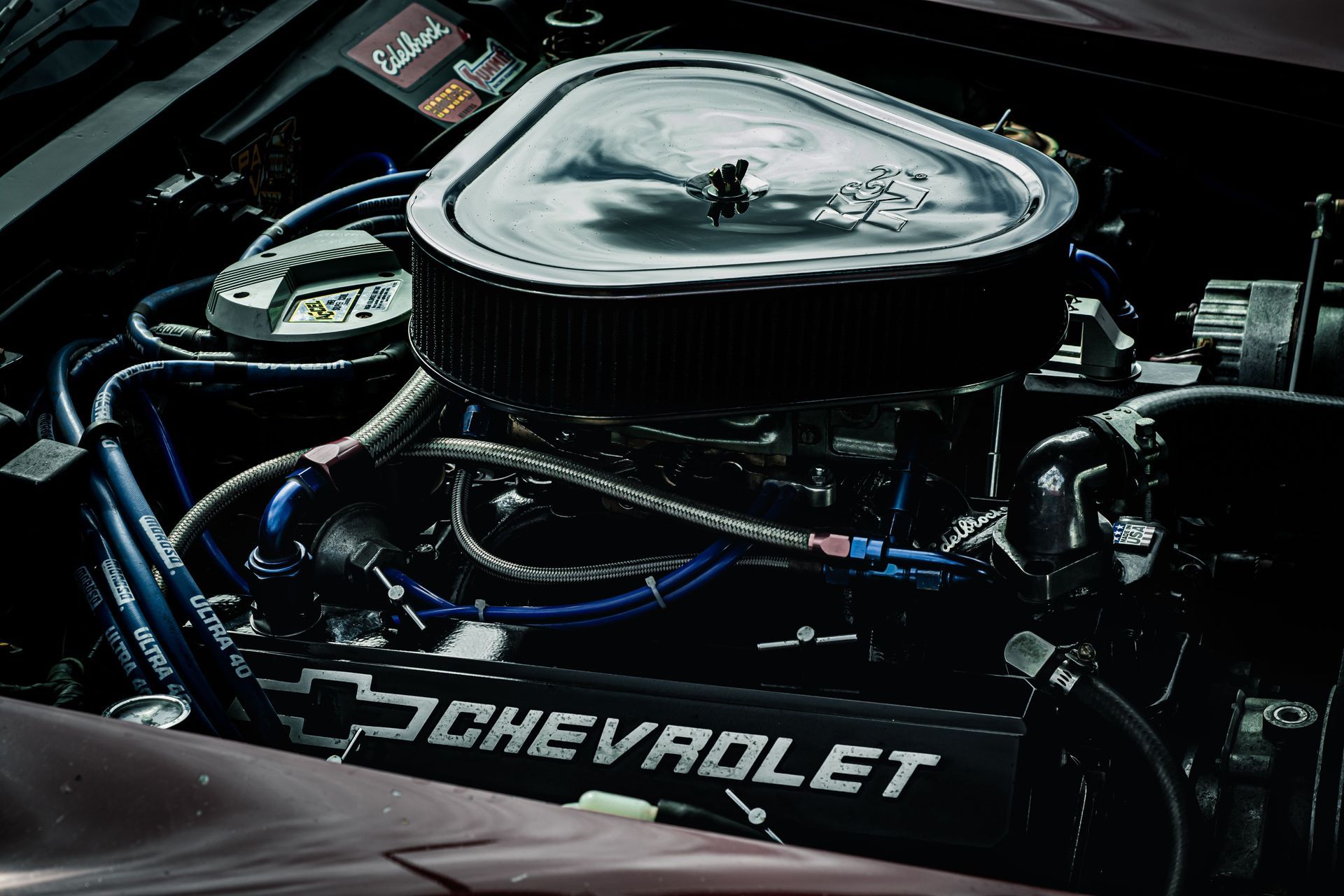Close-up of a Chevrolet V8 engine with chrome air filter and black hoses under the hood.