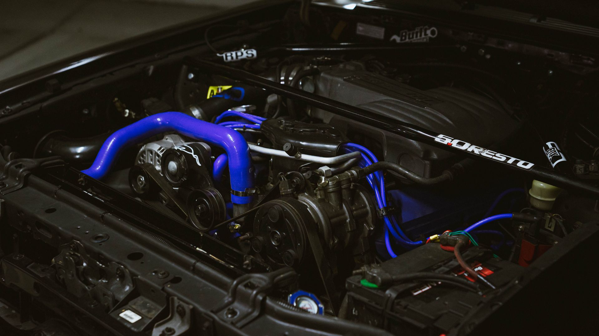 Car engine bay with bright blue intake piping and exposed components under the hood