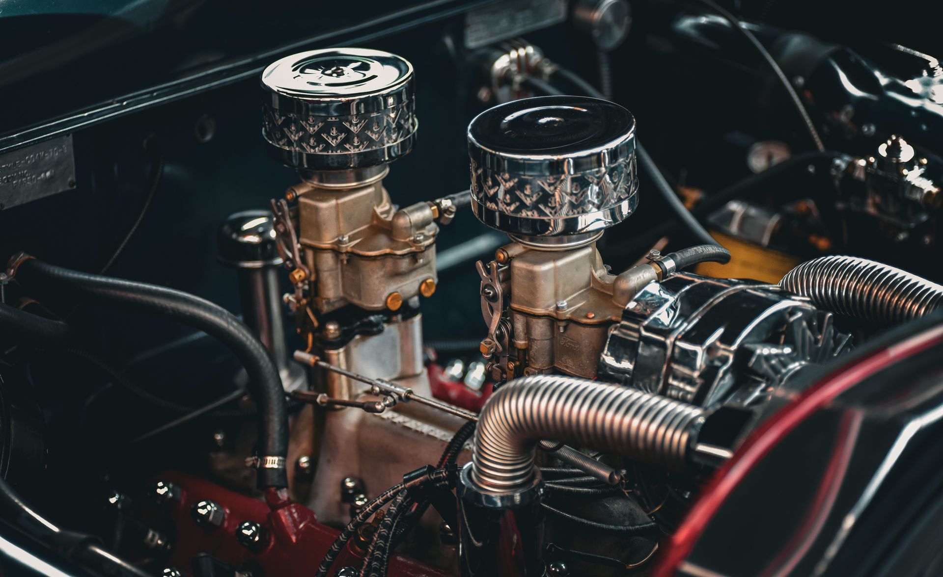 Close-up of a custom car engine with chrome air filters, hoses, and polished metal components.