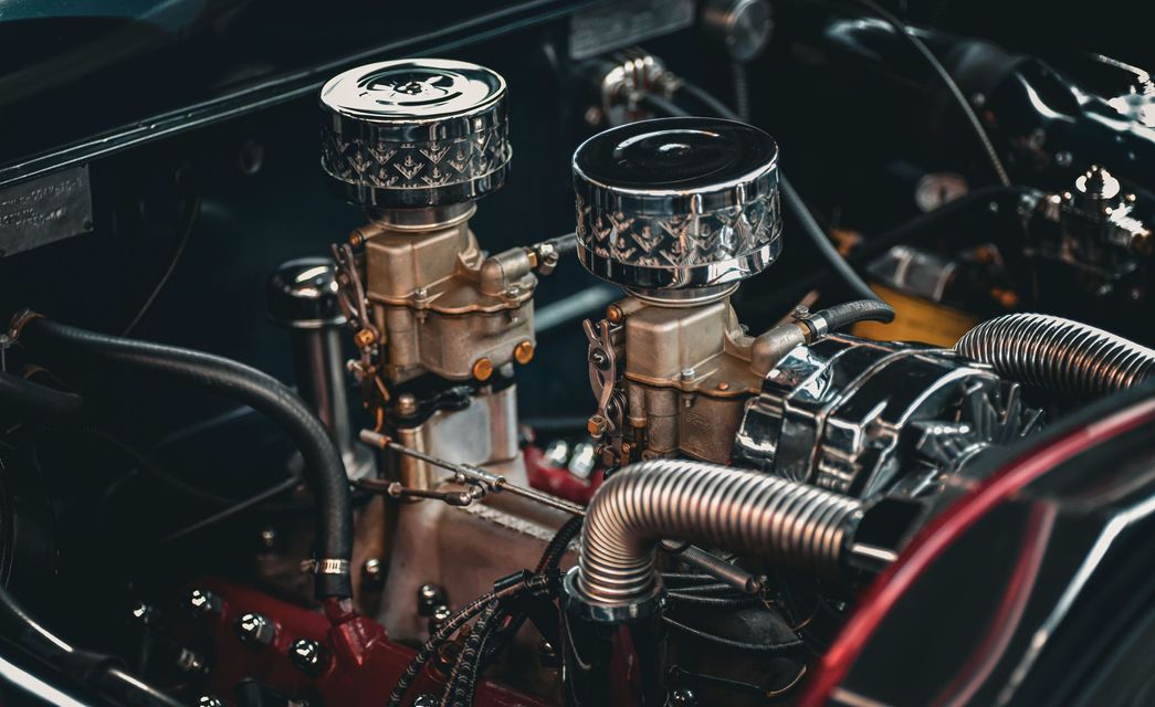Close-up of a custom car engine with chrome air filters, hoses, and polished metal components.