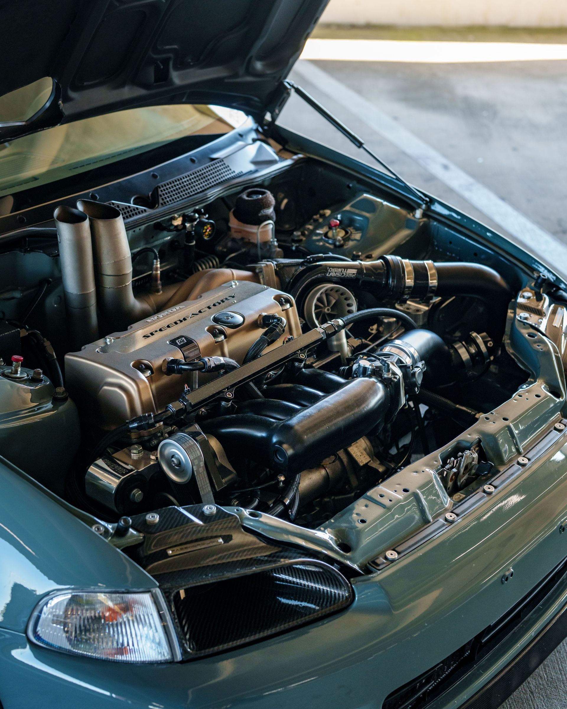 Car engine bay with hood open, showing a modified engine and polished components