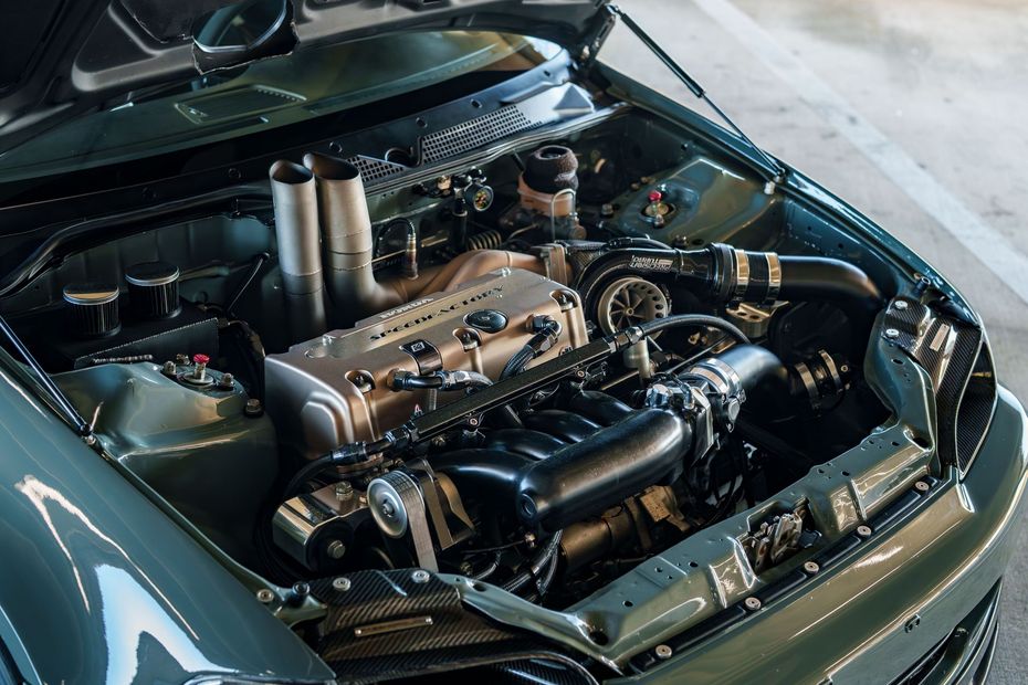 Car engine bay with a large turbo setup and polished intake components, hood open.