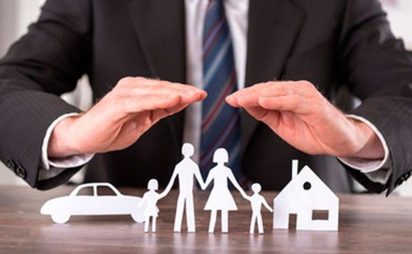 Empresario protegiendo con las manos iconos de papel de familia, casa y coche.
