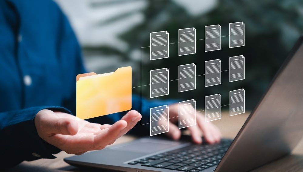 Person using laptop with floating app icons and an orange file folder