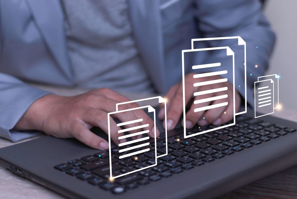 Hands typing on laptop with floating document icons in a digital workflow scene