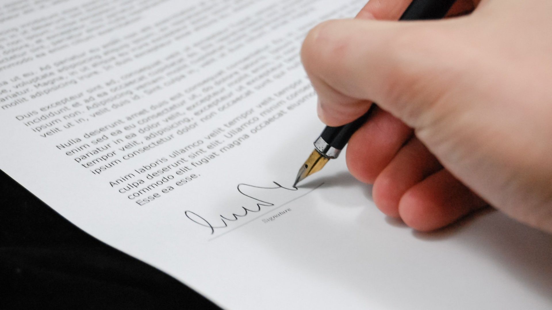 image of a person signing a paper 
document
