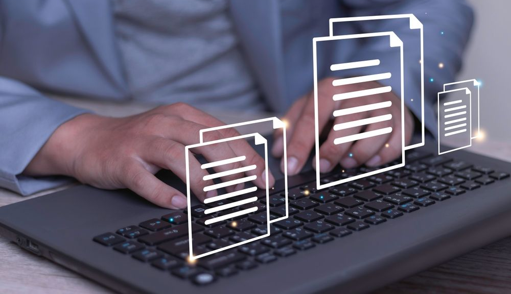 Person typing on a laptop with floating document icons overlaying the screen