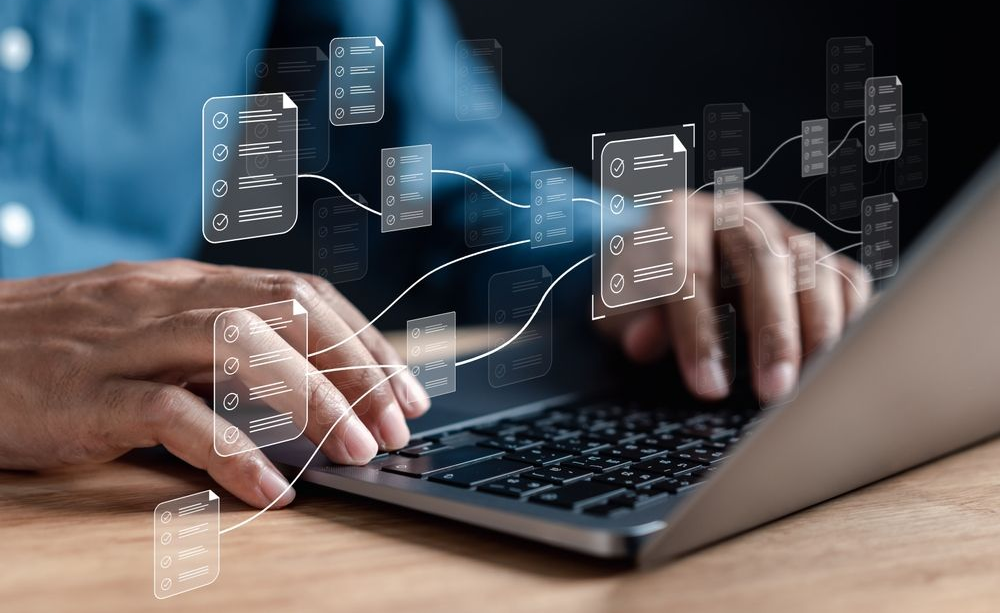 Hands work on a laptop with a digital overlay of a folder and document icons, symbolizing document management.