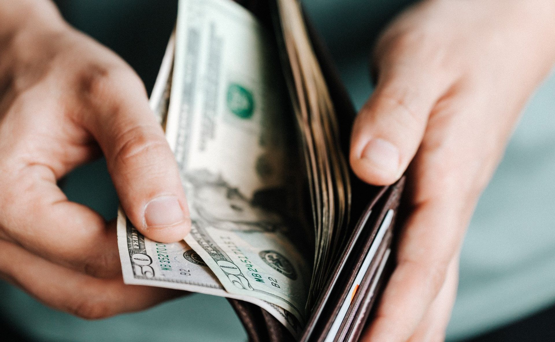 image of man with cash placing in a wallet