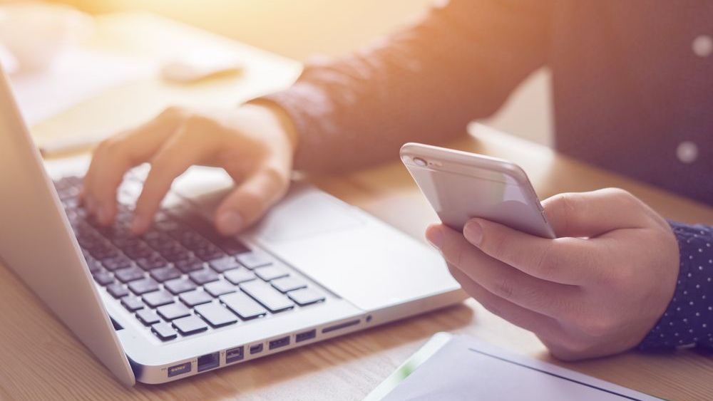image of person interacting with a computer and a phone