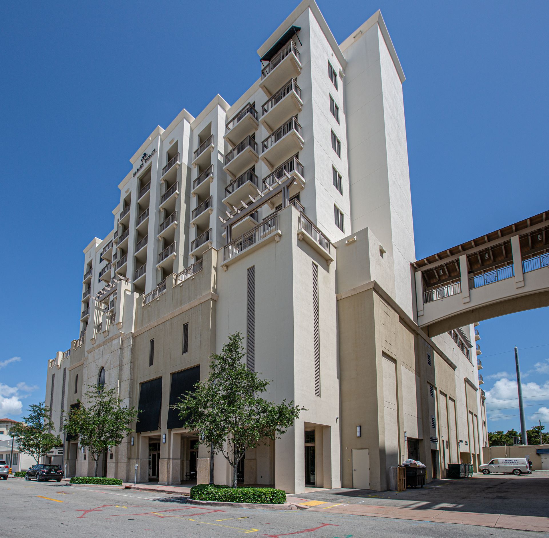Multi-story beige building with balconies, skybridge, and blue sky.