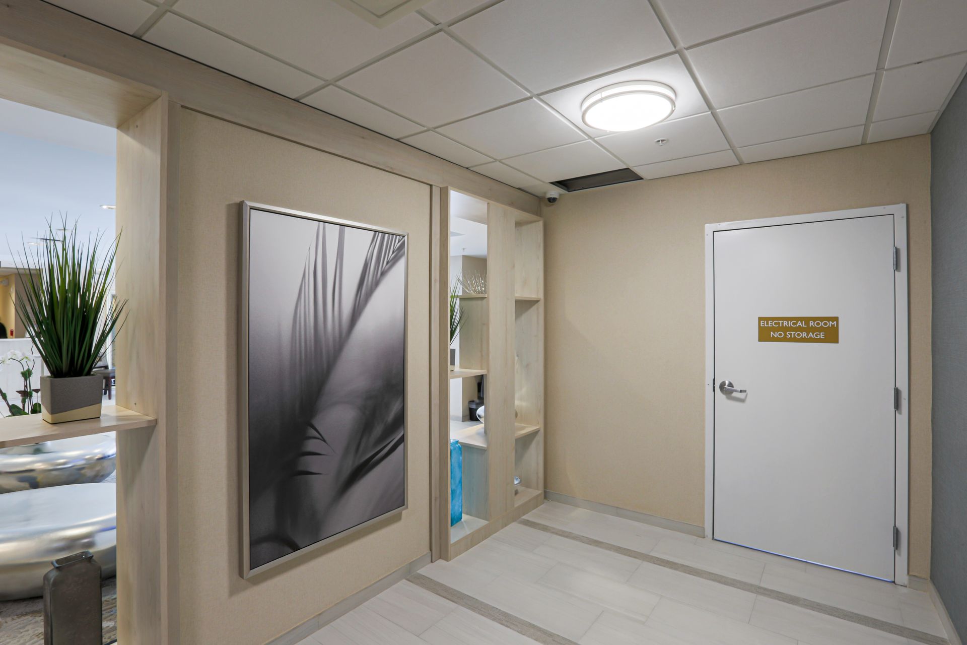 Hallway with beige walls, a white door, and a framed art piece.