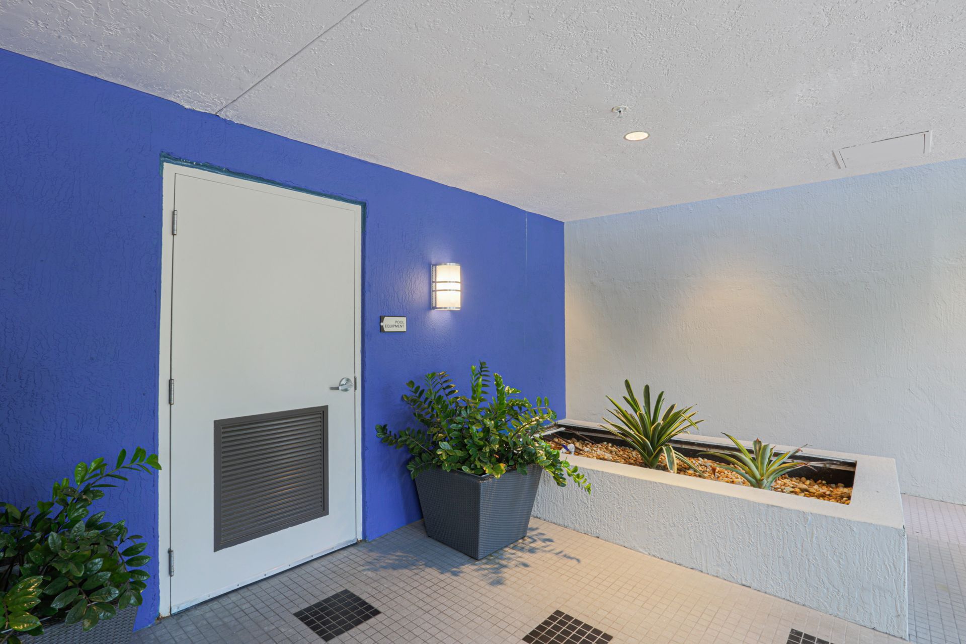 Exterior doorway with blue and white walls, planters, and a white door.