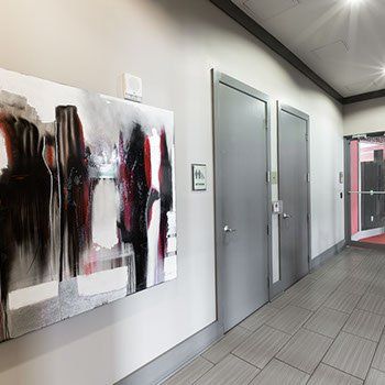 Hallway with abstract art, gray doors, and an exit with red doorframe.