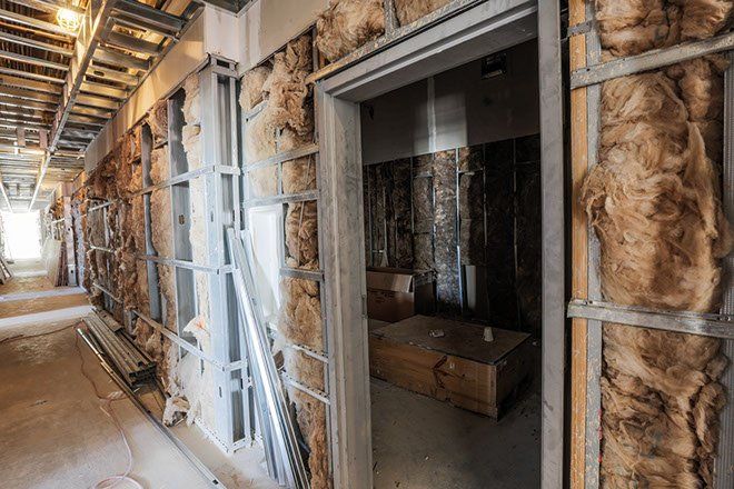 Interior construction: metal studs, insulation, and door frame along a hallway.