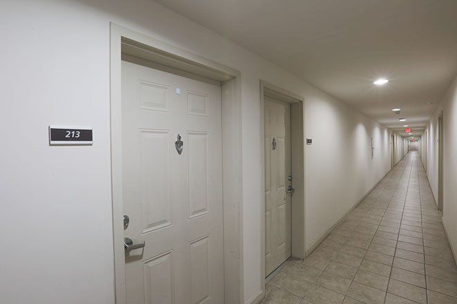 Hallway with white doors and tile floor, leading to a vanishing point.