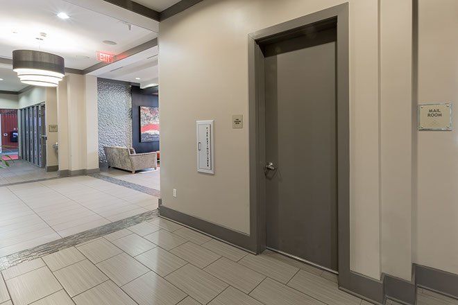 Hallway with an elevator door, fire extinguisher, and seating area.