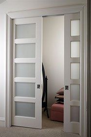 White, frosted glass sliding doors open to reveal an interior space with furniture and light walls.