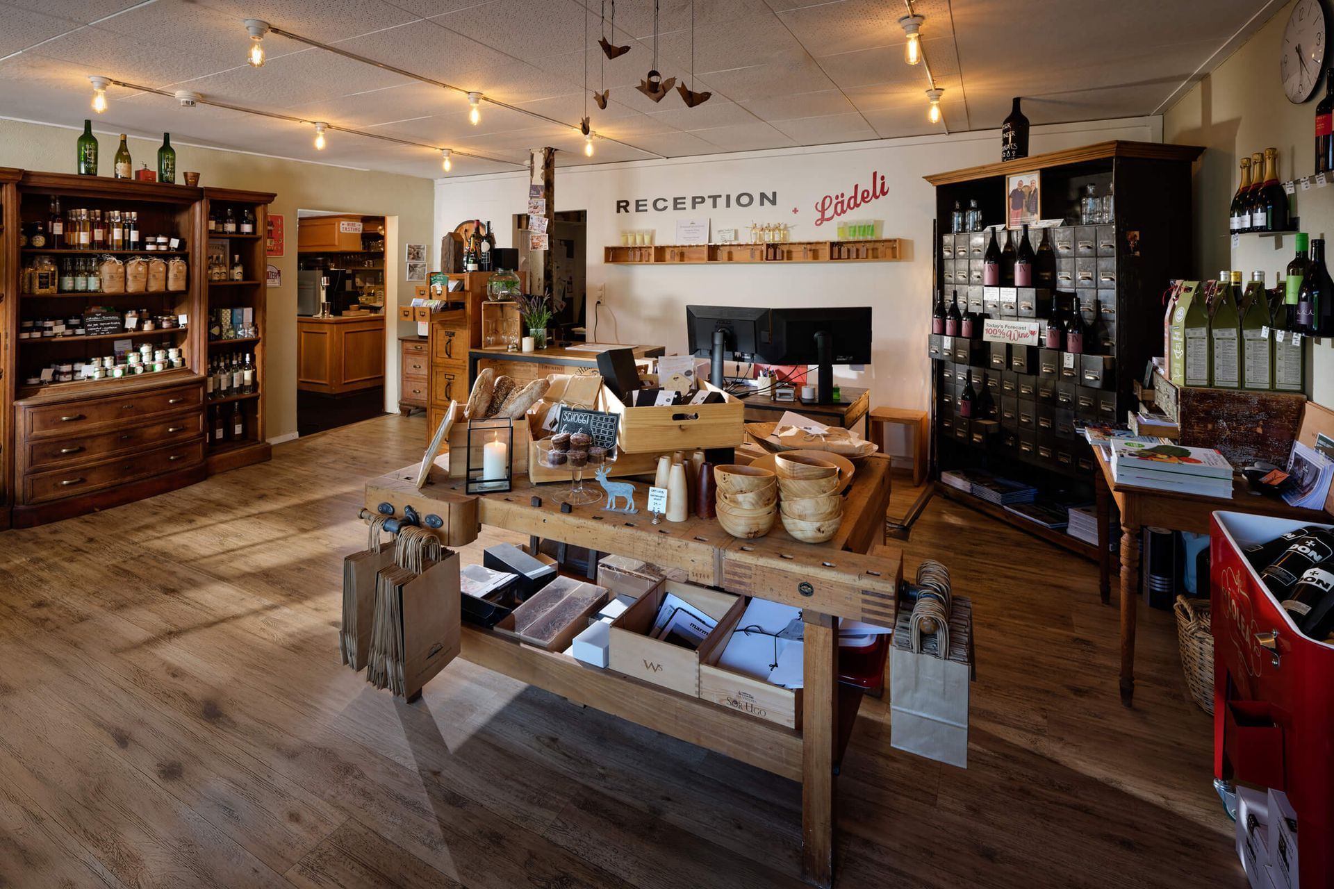 Gemütliches Weinladeninterieur mit Holzregalen, Tischen, Flaschen und warmen Lichterketten