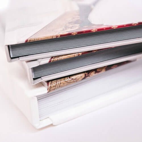 Stacked photo albums with ornate covers on a white surface