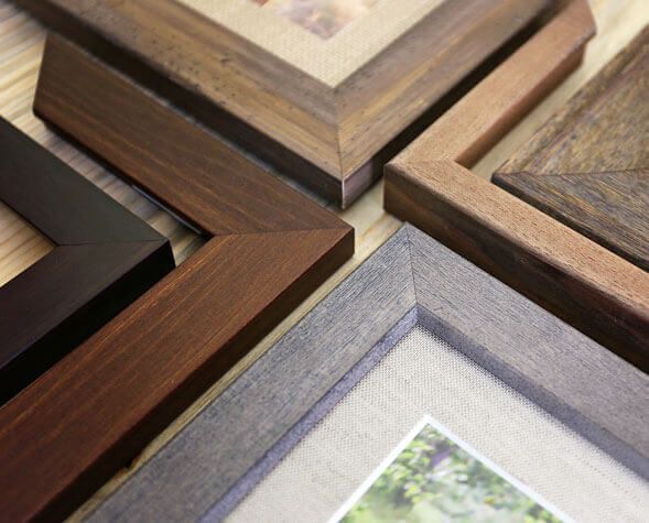Close-up of stacked picture frame corners in brown, black, and gray wood tones