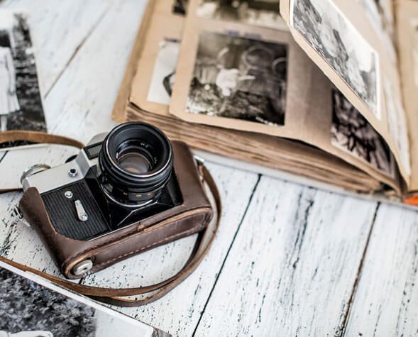Vintage camera on a white wooden table beside an open photo album.