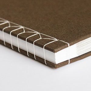 Brown spiral-bound notebook with white pages on a white surface