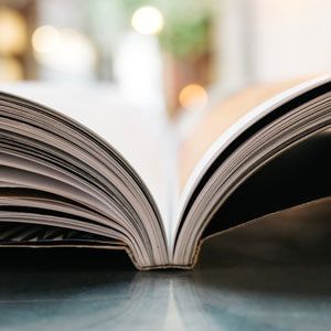 Open book on a table with pages fanned out, blurred warm background