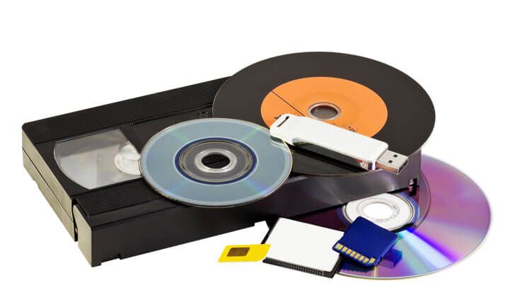 Stacked VHS tape, floppy disks, and CDs representing outdated storage media