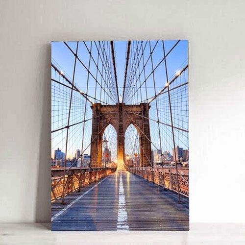 Brooklyn Bridge walkway viewed head-on, with stone arches and cables against a blue sky
