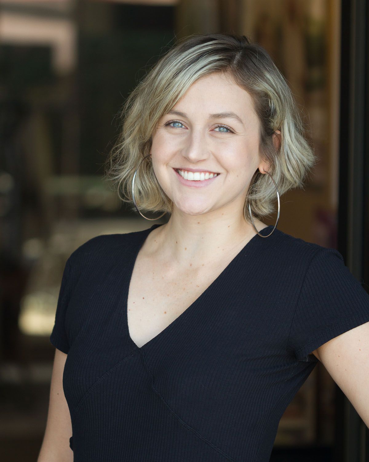 Smiling person in a black shirt against a softly blurred indoor background