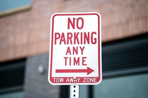 Red and white “No Parking Any Time” tow-away zone sign on a pole.