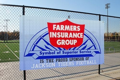 Banner for Farmers Insurance Group, sponsor of Jackson Tigers football, on a chain-link fence at a field