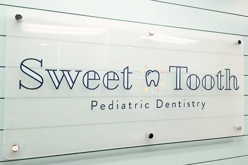 Sweet Tooth Pediatric Dentistry sign on a frosted glass wall