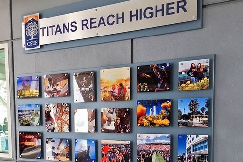 Wall display with “Titans Reach Higher” sign above a grid of colorful campus photos
