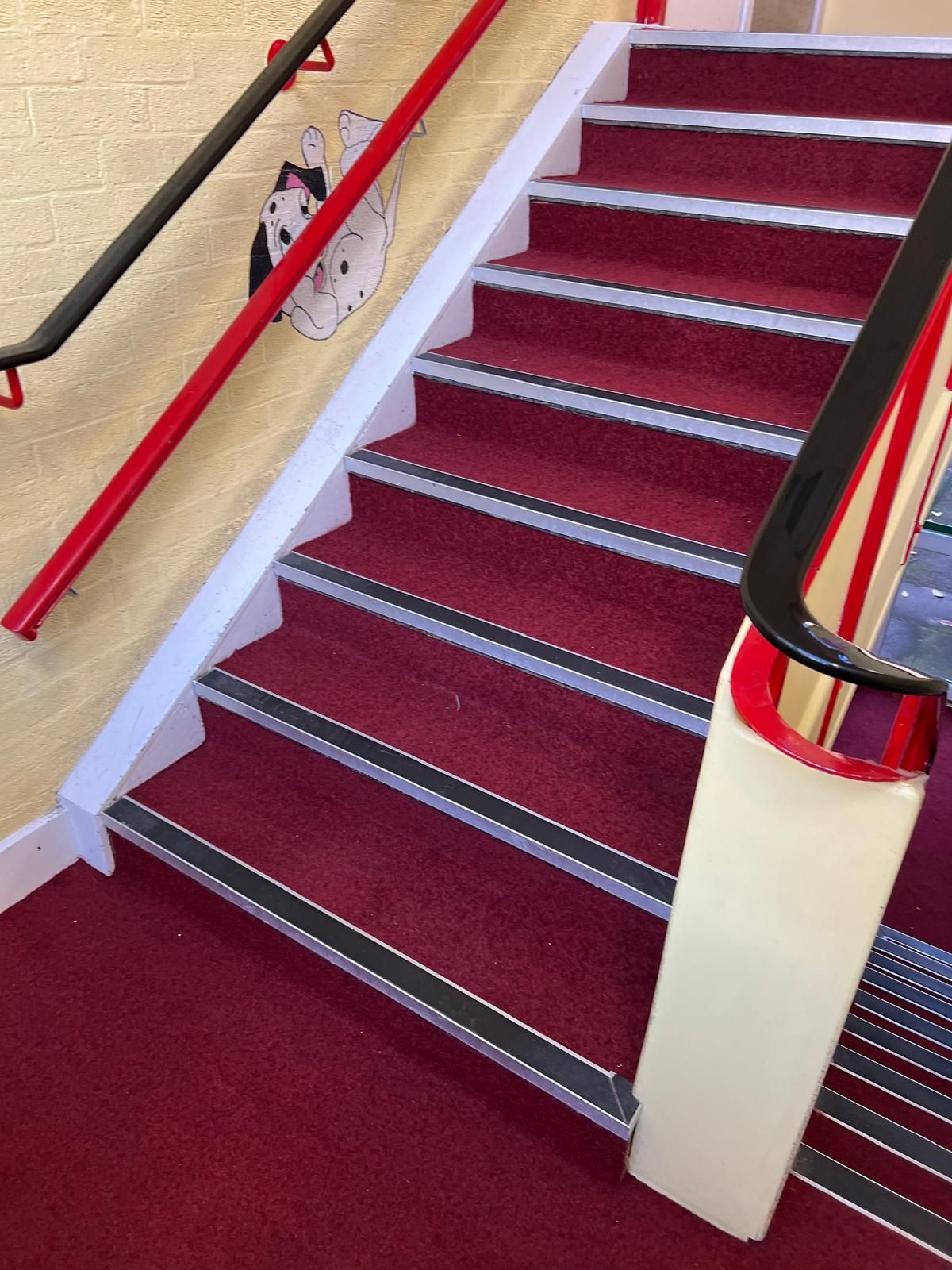 Red carpeted staircase with white and black accents; red and black handrails.