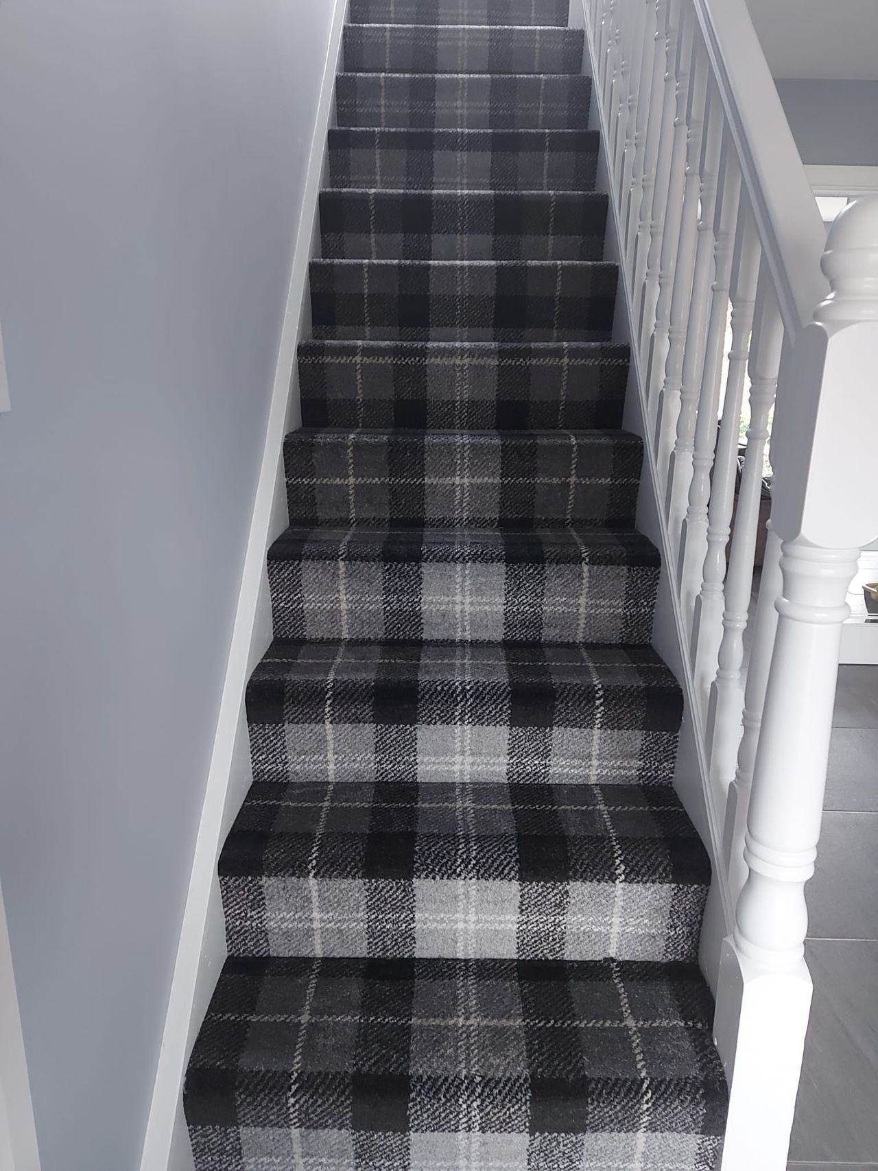 A black and white photo of a staircase with a plaid carpet.