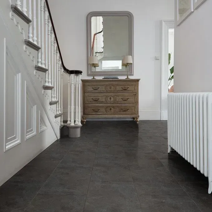 A hallway with stairs a dresser and a mirror