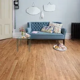 A living room with a blue couch and a wooden floor.