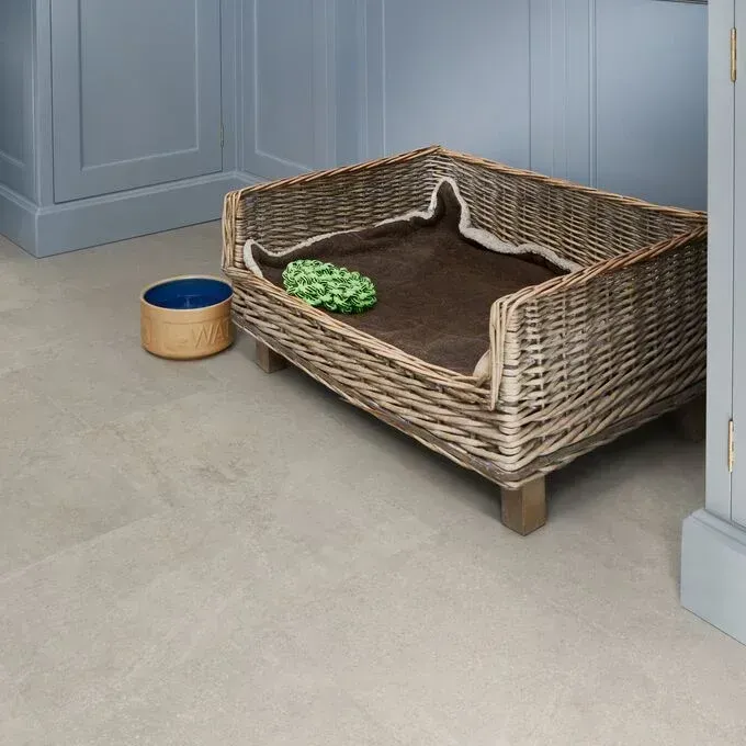 A wicker dog bed is sitting on the floor next to a bowl