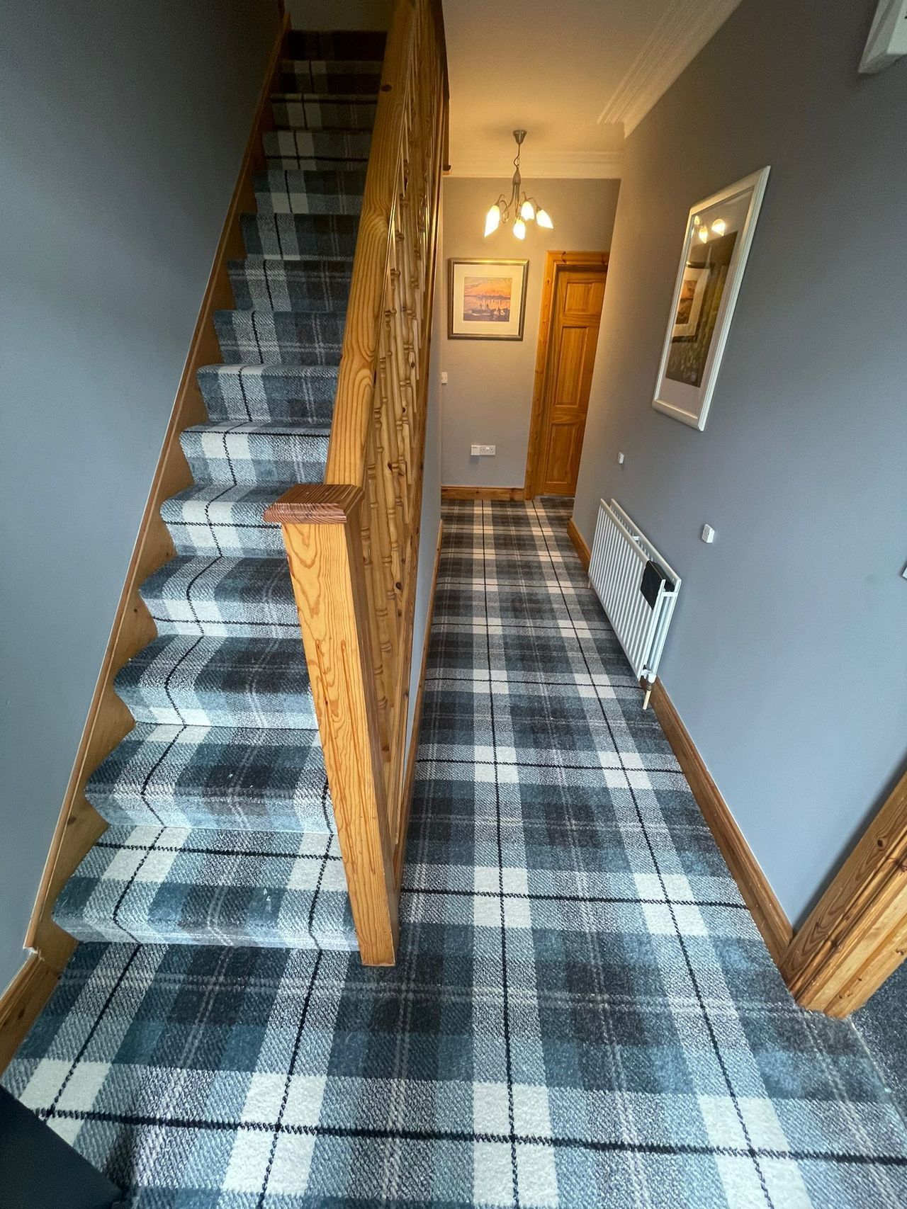 A hallway with stairs and a plaid carpet.