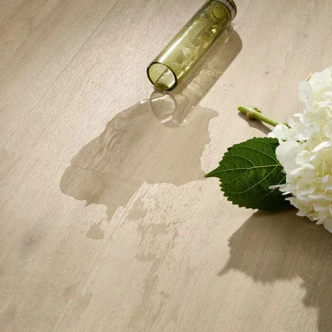 A bottle and a flower on a wooden floor