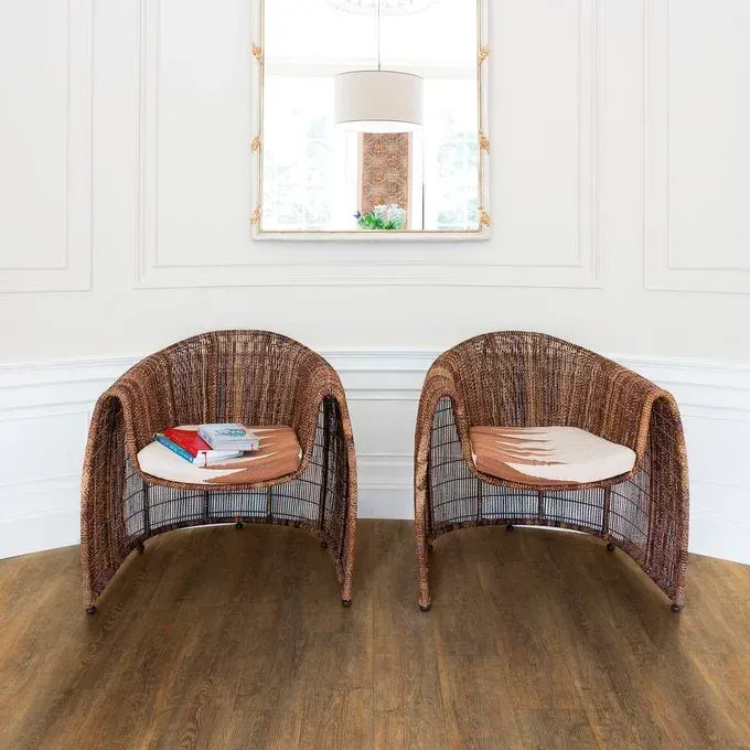 Two wicker chairs are sitting next to each other on a wooden floor in a living room.